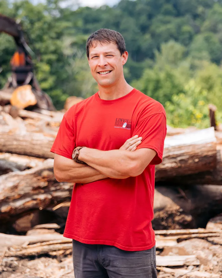 Jeb Carter, second-generation owner of Linville River Company, standing in front of a log pile at the Newland yard