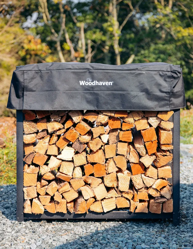 A Linville River Company rack stacked full of split firewood with a fitted black cover